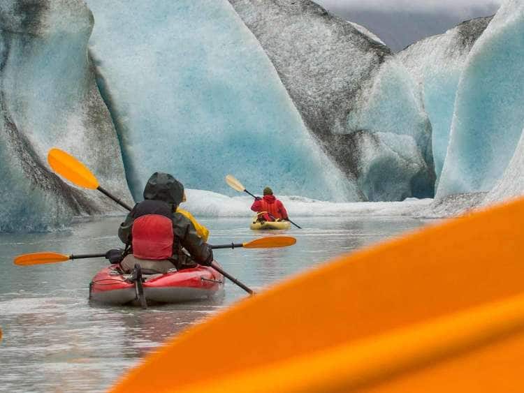 Kayakers paddling near an Alaska glacier on a shore excursion