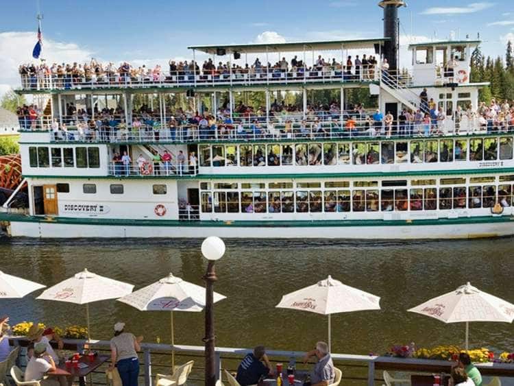 Guests on the deck of the Chena Pump House restaurant watch the riverboat Discovery pass by on the Chena River in Fairbanks, Alaska.