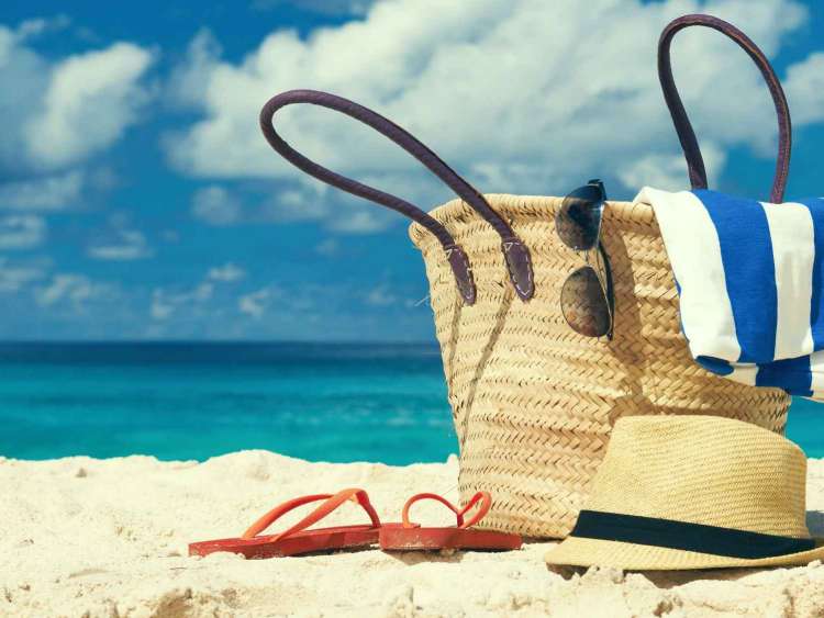 Packed tote bag on beach with hat and sandals