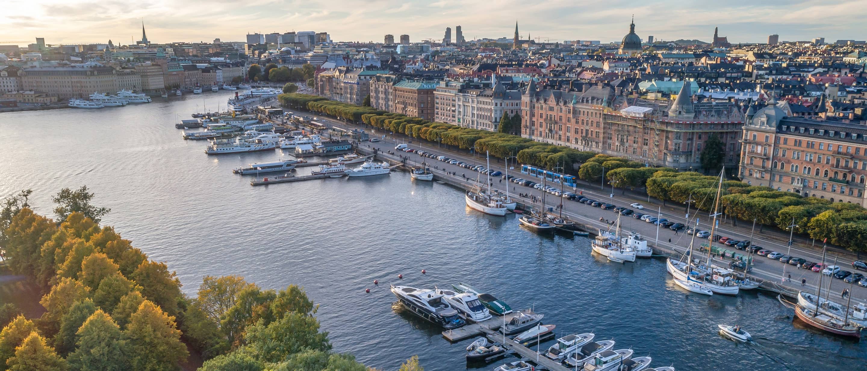 Ostermalm District Canal with boats docked along the shore, surrounded by greenery and buildings under a clear sky.