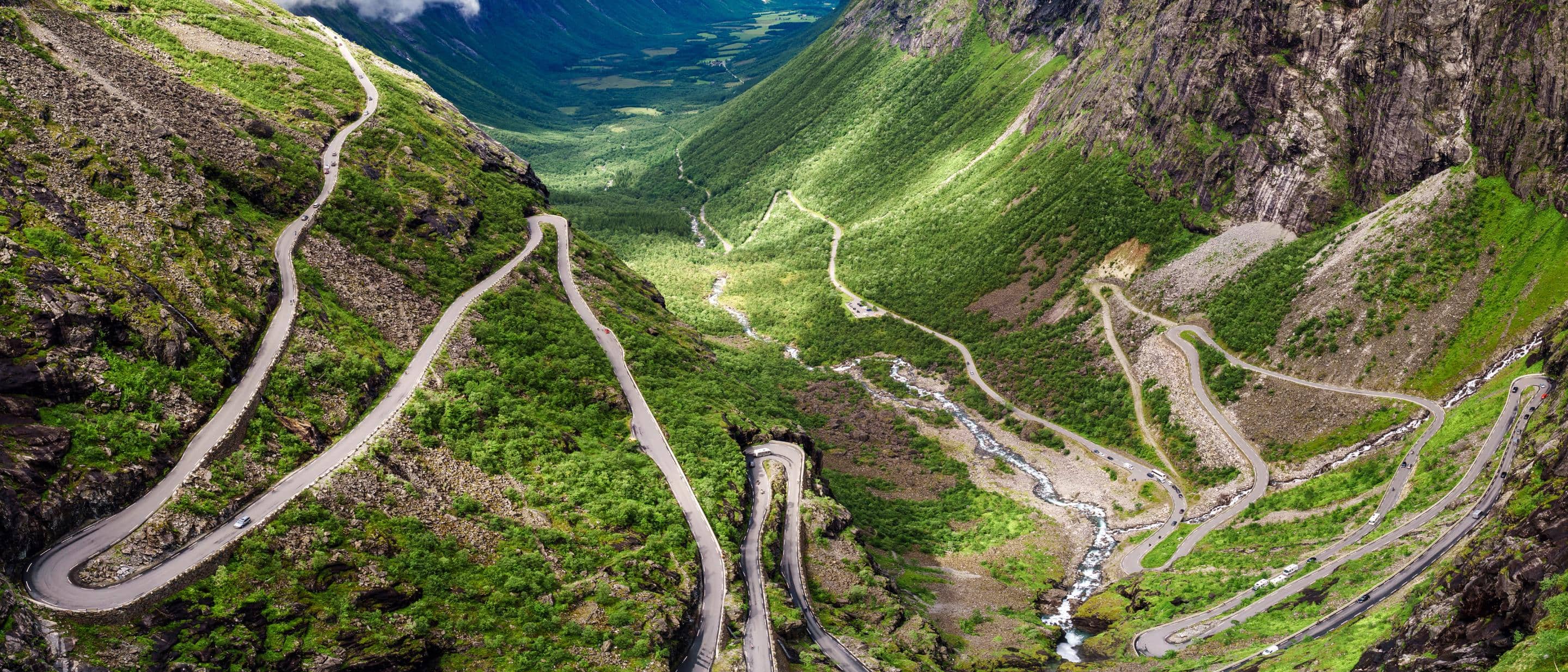 Winding mountain road with sharp turns and a river below.