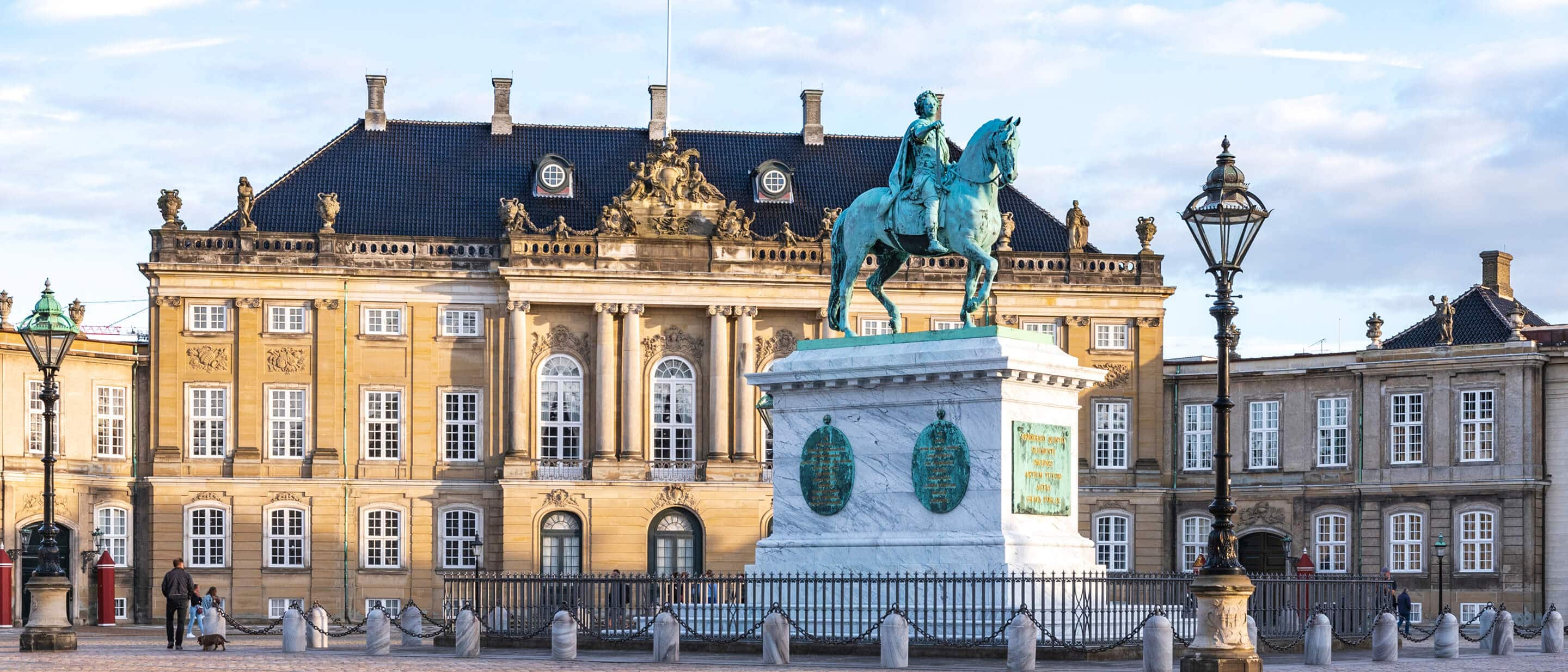 Statue of a man on a horse sits on a plinth in front of the Amalienborg Palace in Copenhagen, Denmark.