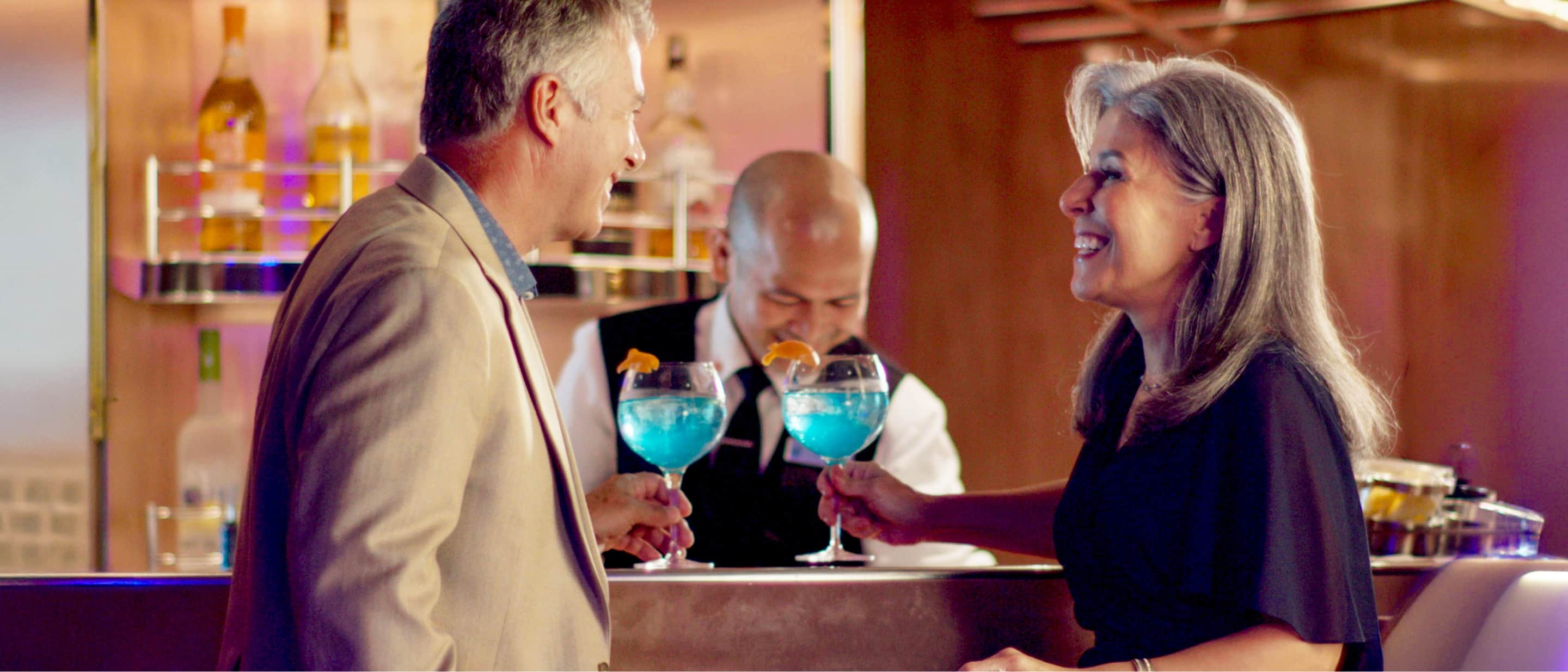 A couple enjoying blue cocktails at the Billboard bar onboard a Holland America ship.