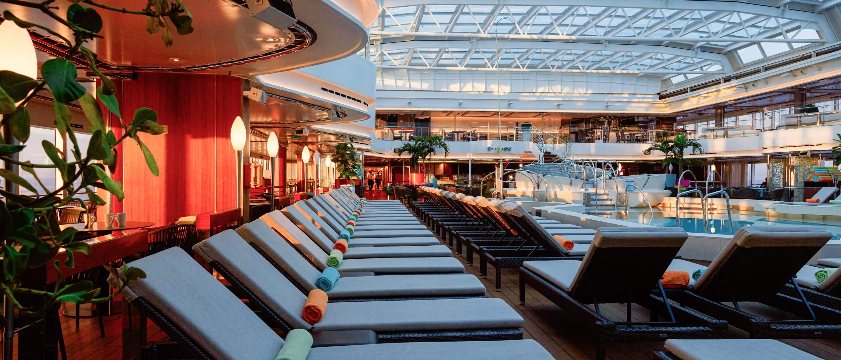Lido Pool on Holland America cruise ship with spacious deck, loungers, and glass roof for all-weather swimming.