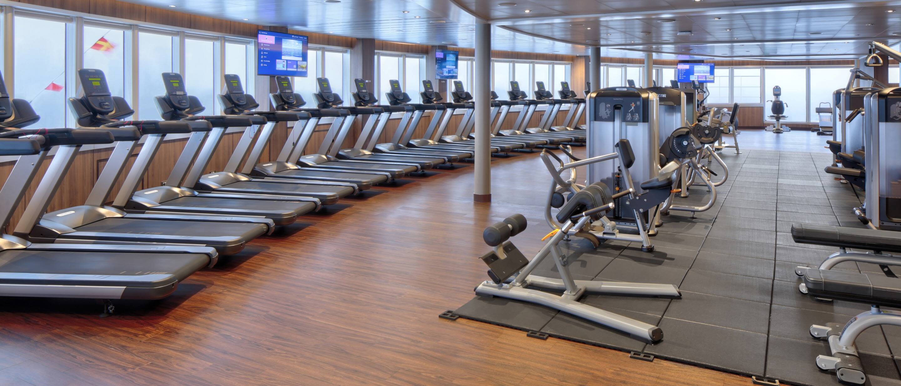 Fitness Center on a Holland America cruise ship with treadmills, strength machines, and panoramic ocean views.