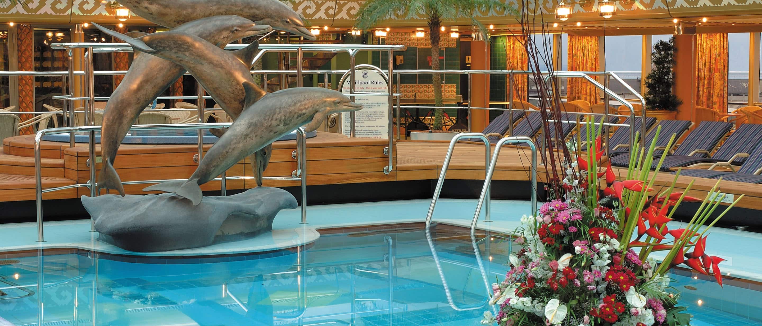 Lido Pool deck area with a sculpture of dolphins leaping out of the water, aboard the Holland America Line ship.