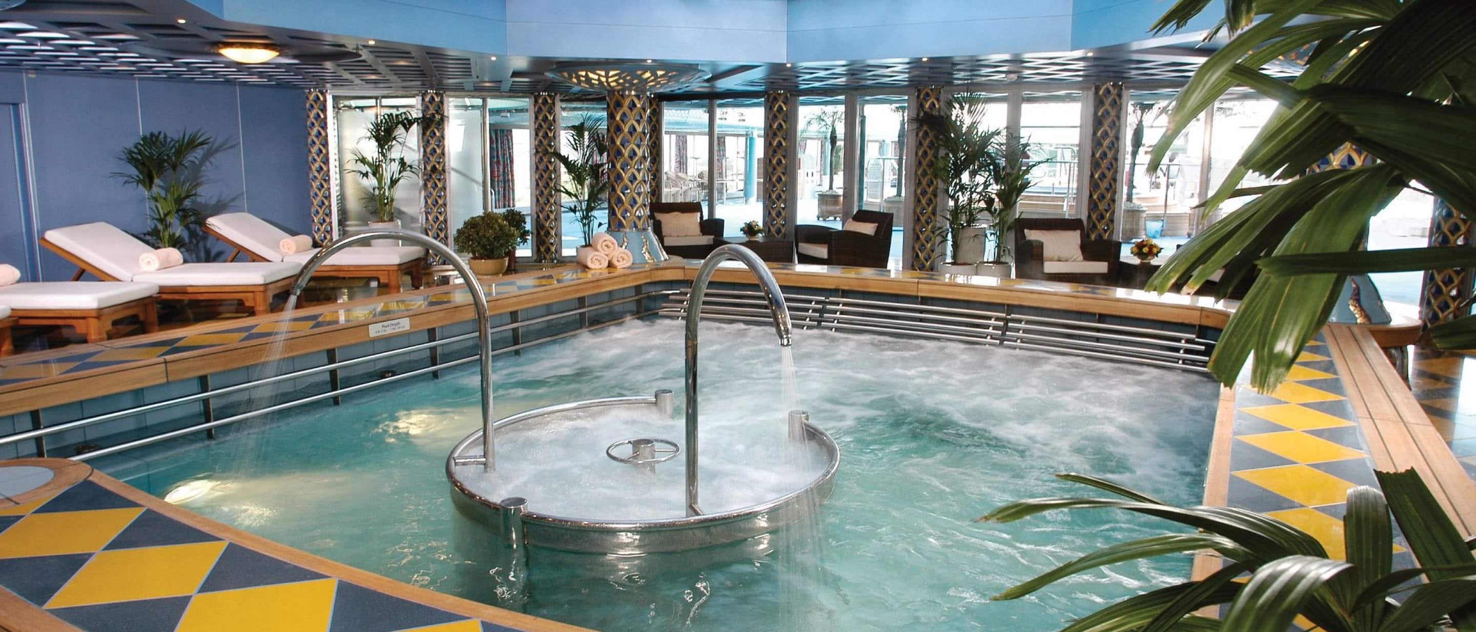 Hydropool on a Holland America cruise ship with water jets, metal handrails, lounge chairs, and surrounding plants.
