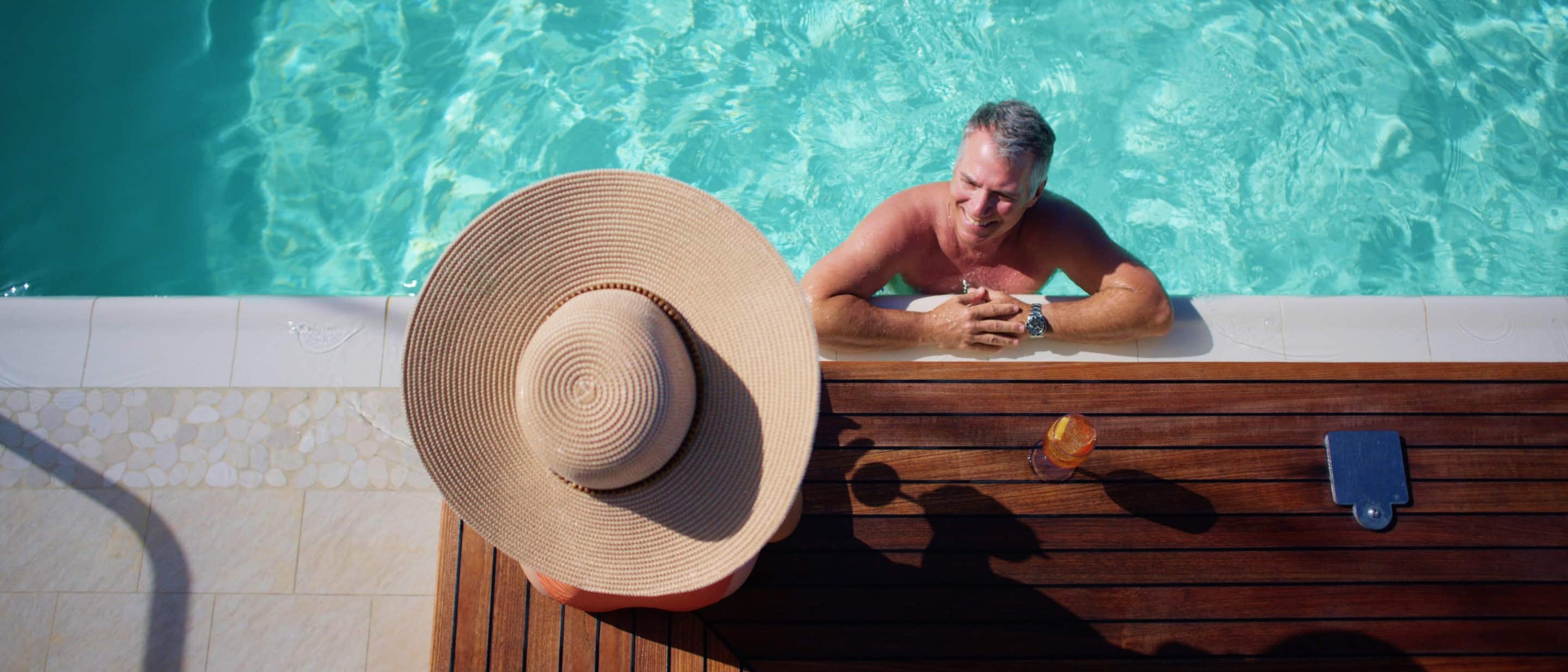 Top view of guests relaxing at the Sea View Pool beside a sunbather on a Holland America cruise ship.