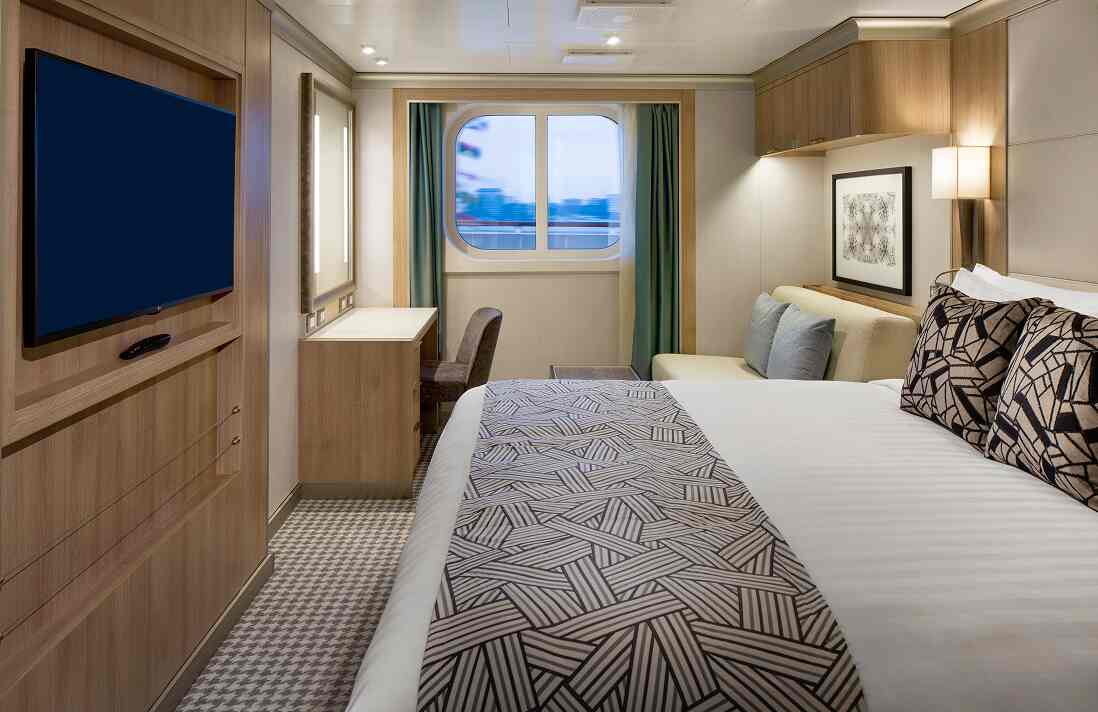 Ocean View Stateroom with queen bed, wall-mounted TV, desk and framed artwork on a Holland America cruise ship.
