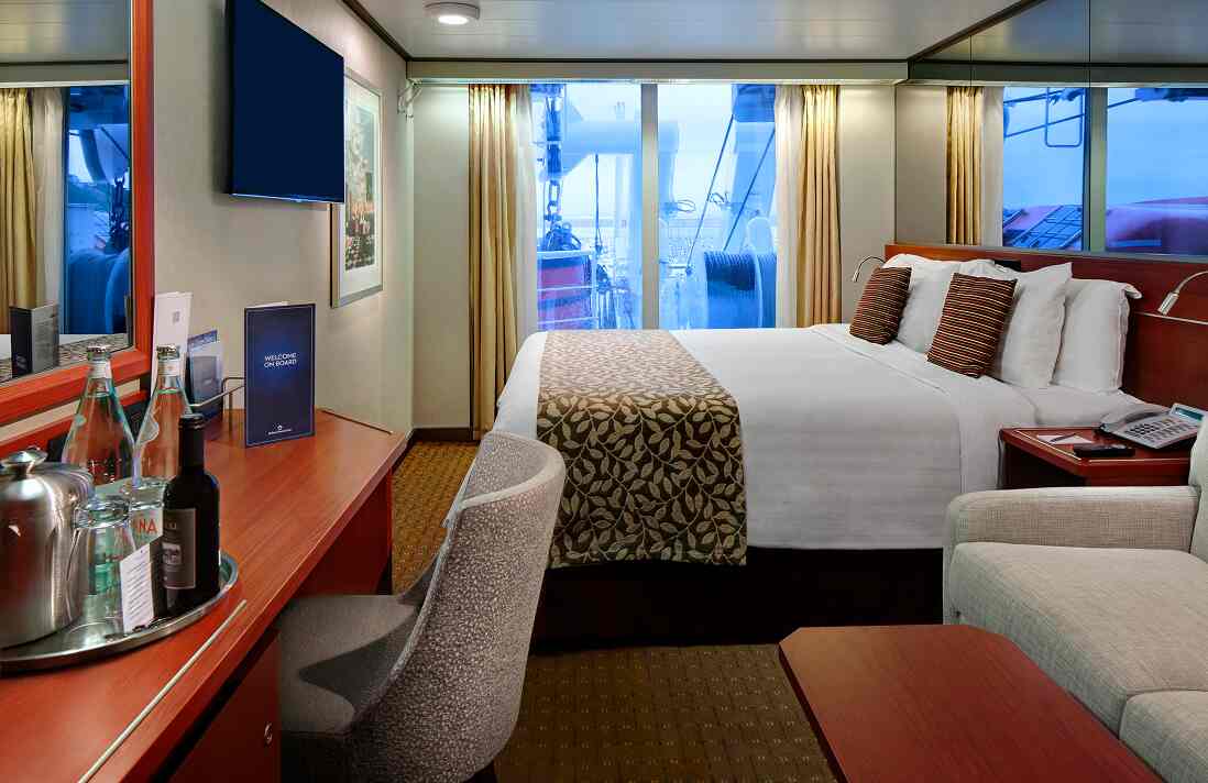 Partial Obstructed Ocean View stateroom with queen bed, desk, and window on Holland America cruise ship.