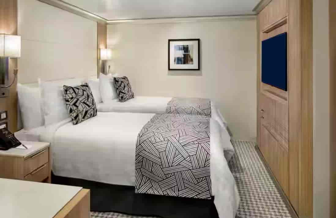 Spa Inside Stateroom on a Holland America cruise ship with two twin beds, wall-mounted TV and light wood cabinetry.