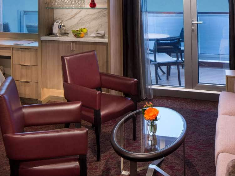 Sofa and two chairs around a glass coffee table in the Neptune suite aboard Koningsdam