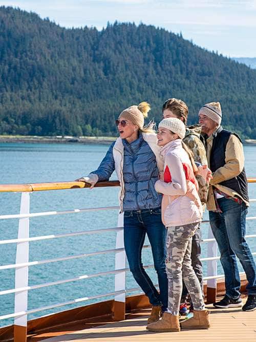 Family on ship's bow experiencing Alaska's shores