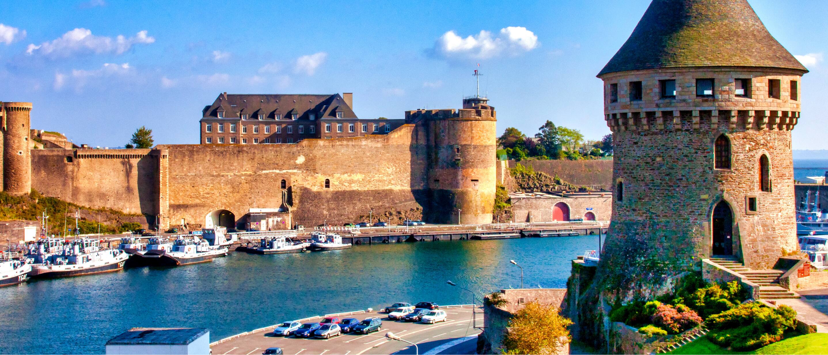 Brest Castle overlooking the harbor with stone towers and docked boats in Brittany, France.