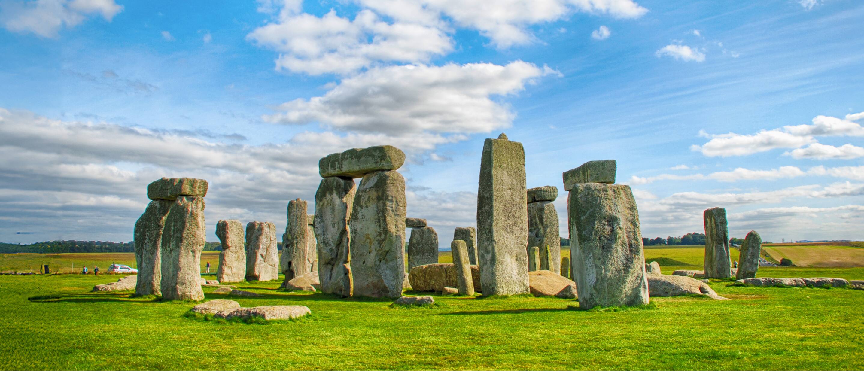 Stonehenge prehistoric stone circle standing on a grassy plain under a blue sky in England.