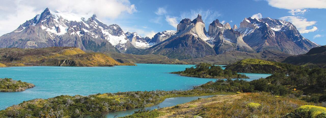 A body of water in the foreground with snow-capped mountains in the background.