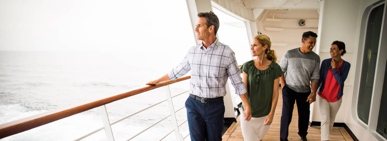 Couples walk along the promenade of a Holland America Line cruise ship.