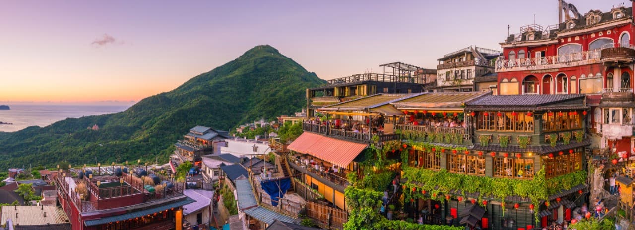 A view of the city in Taiwan with green mountains and water in the background.