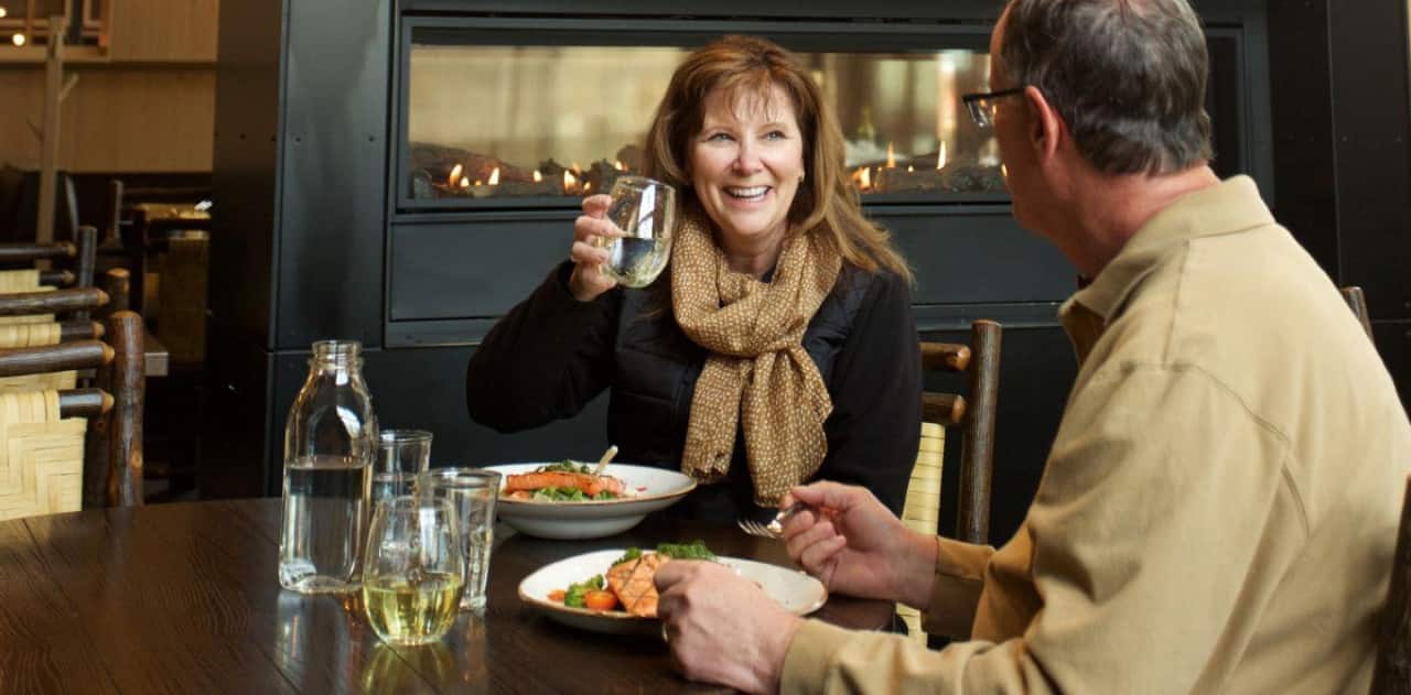 Couple enjoying a meal at an Alaska lodge during a Holland America Line land and sea Cruisetour.