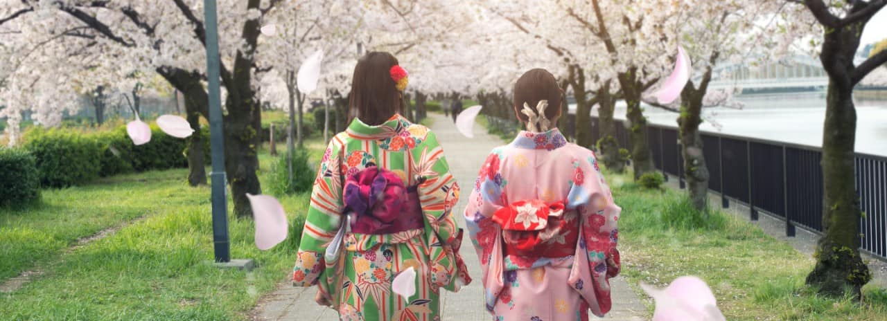 Two women dressed in colorful clothing walking down a path in Japan.
