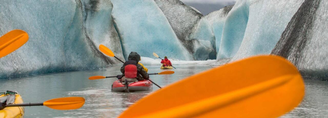 Kayakers paddling near an Alaska glacier on a shore excursion