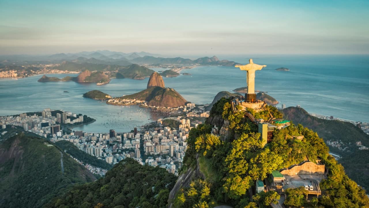 Aerial photo near Rio de Janeiro, Brazil with Sugarloaf Mountain and the famous Christ the Redeemer statue visible in the distance.