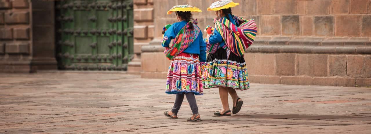 Two indigenous women walking in a square in Peru.