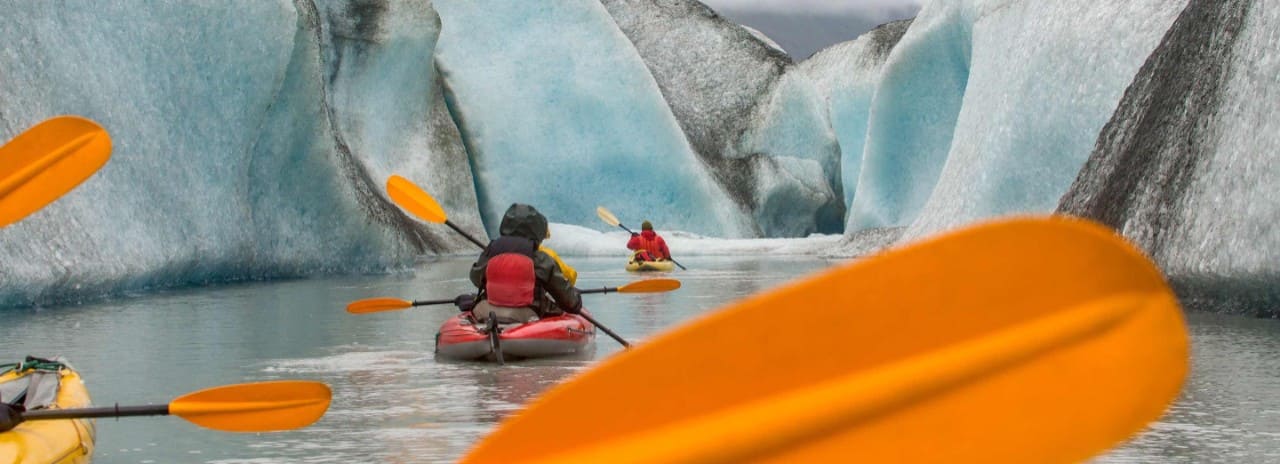 Kayakers paddling near an Alaska glacier on a shore excursion
