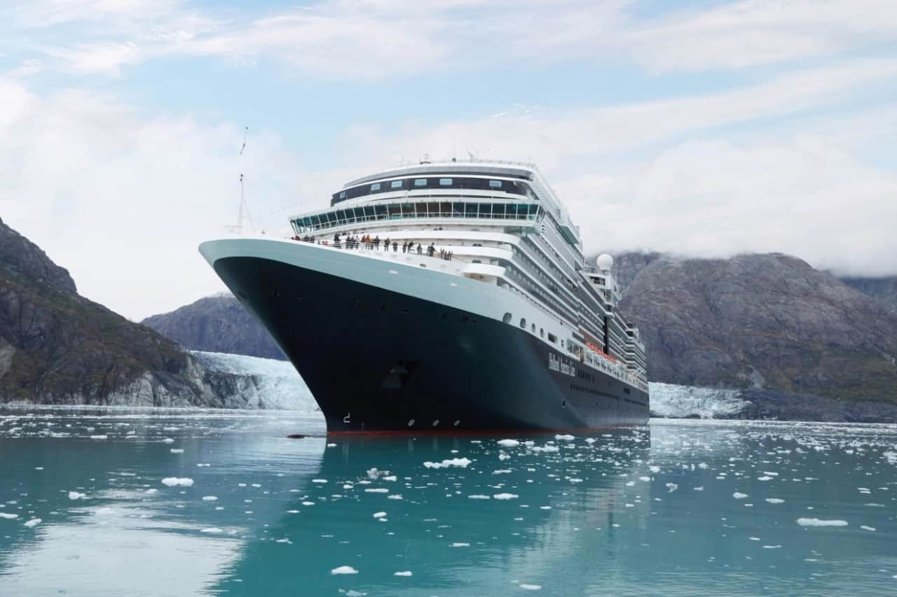 Couple on a cruise ship deck admiring Alaska’s snowy mountains and icy waters.