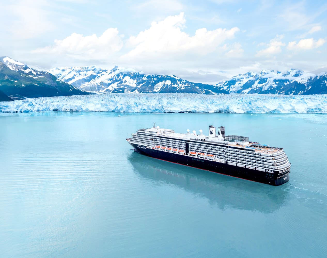 Holland America Line cruise ship in scenic Alaskan fjord near Hubbard Glacier and snow-capped mountains