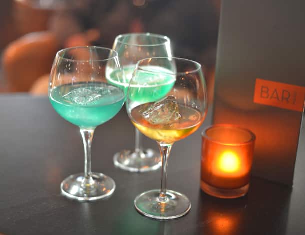 Three glacial ice cocktails and a candle on a bar table aboard a Holland America Alaska cruise