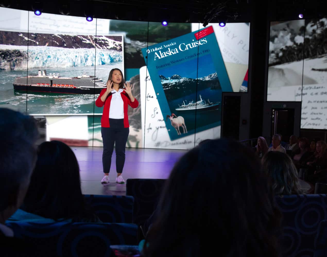 Woman on stage presenting Alaska Up Close program aboard a Holland America cruise