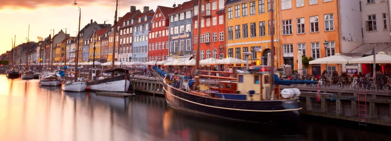 Boats along the waterfront in front of many colorful buildings in Copenhagen, Denmark.