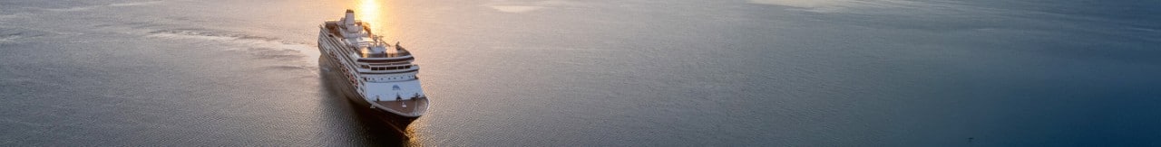 Holland America Line's Volendam cruise ship sailing on smooth waters filled with the sun's reflection.