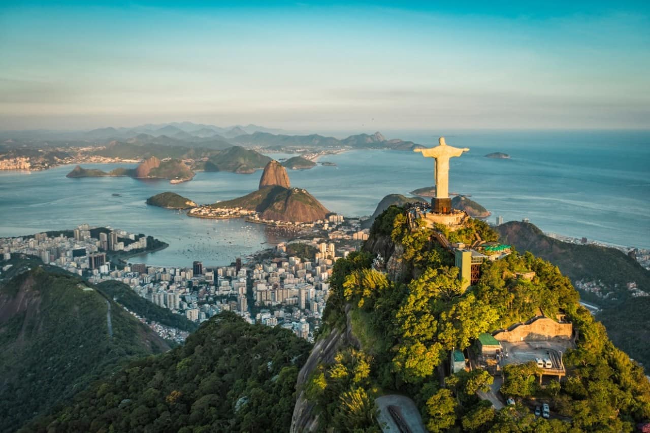 Aerial view of Rio de Janeiro, Brazil with statue of Christ the Redeemer and Sugarloaf mountain seen in the distance.