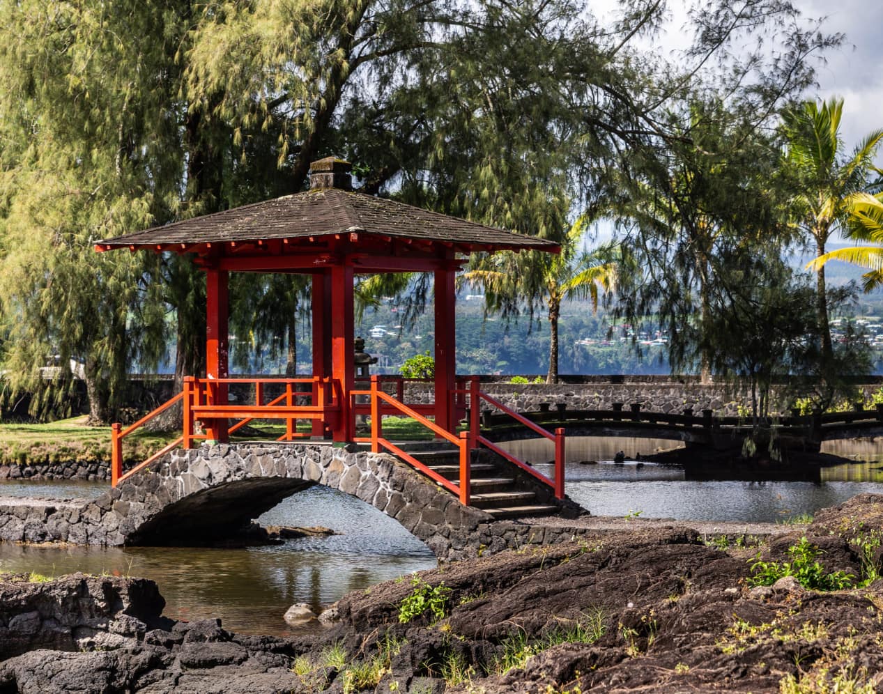 A covered walkway across a pond in a park in Hilo, Hawaii