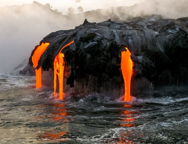 view of a lava flow dripping into the ocean