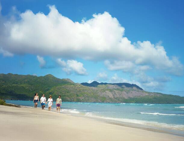 a family walking along a sunny, sandy Hawaiian beach 