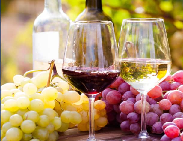 Wine glasses on a table with grapes.