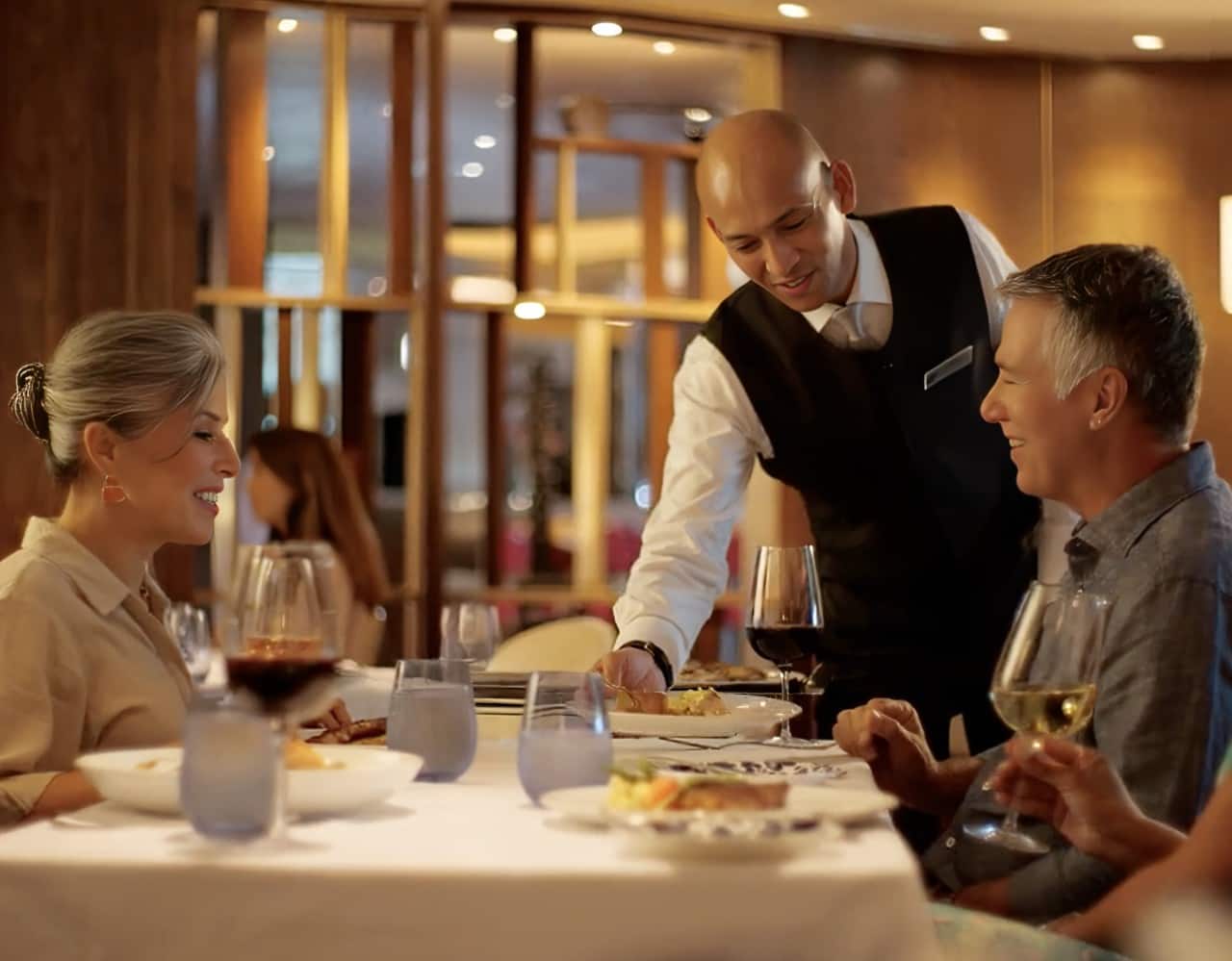 A waiter serving dinner to a couple
