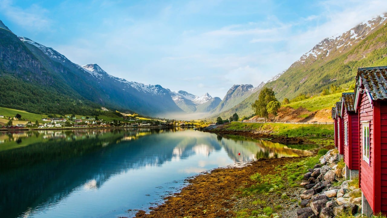 Traditional red wooden cabins on the shore of a Norwegian fjord.