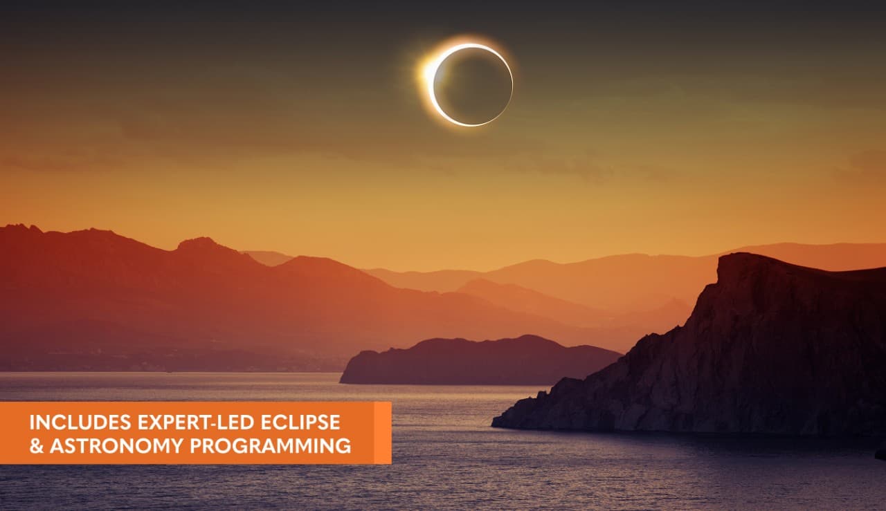 Warm colors of sunset over mountainous coastline with a solar eclipse centered in the sky above. Overlay reads 'includes expert led eclipse & astronomy programming'.