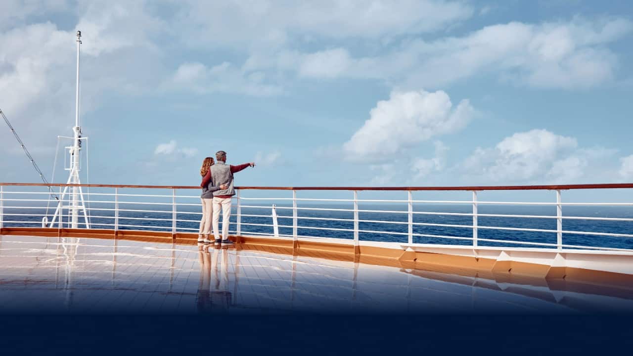 Couple looking out at the ocean from cruise ship deck.