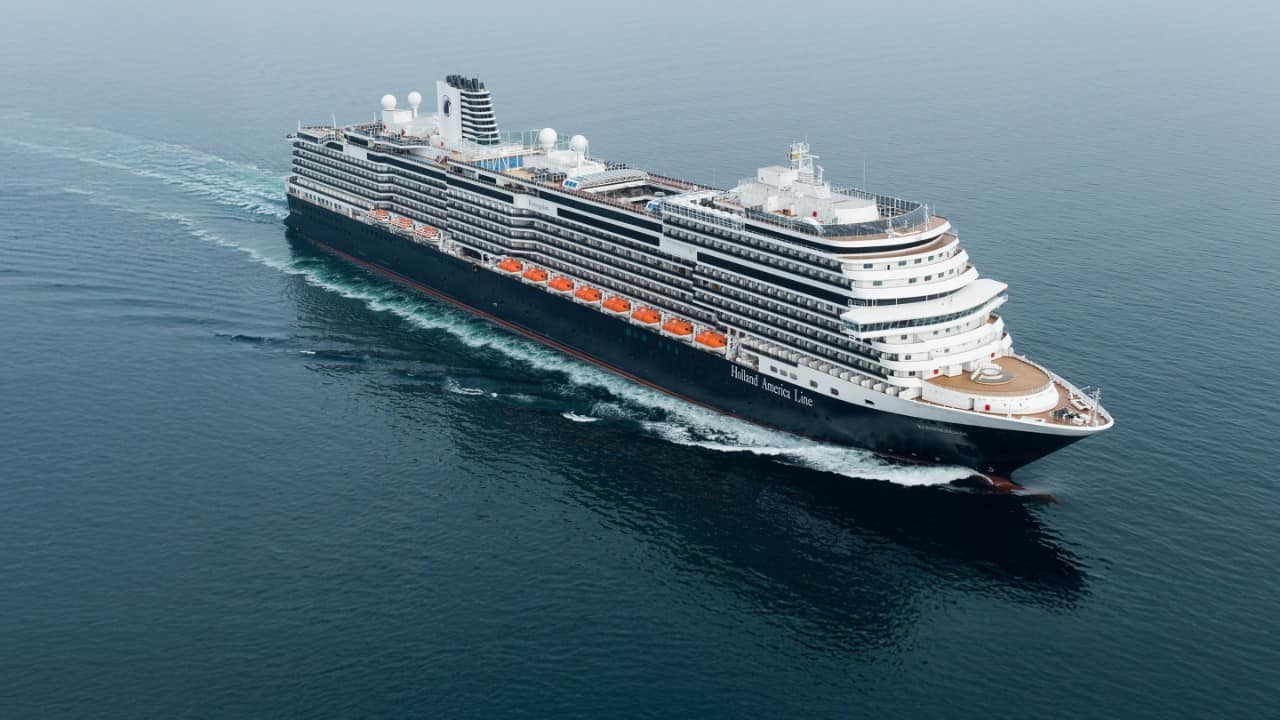 Person stretching in bed inside a Holland America cruise stateroom.