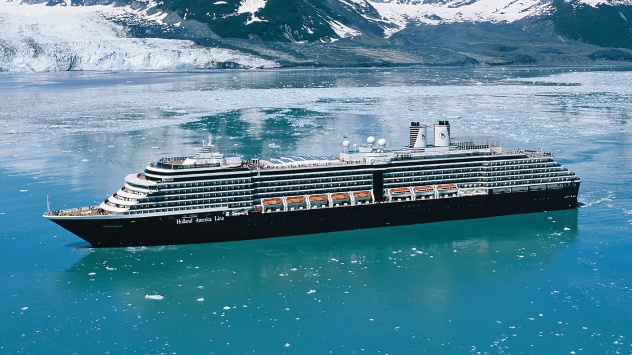 Person stretching in bed inside a Holland America cruise stateroom.
