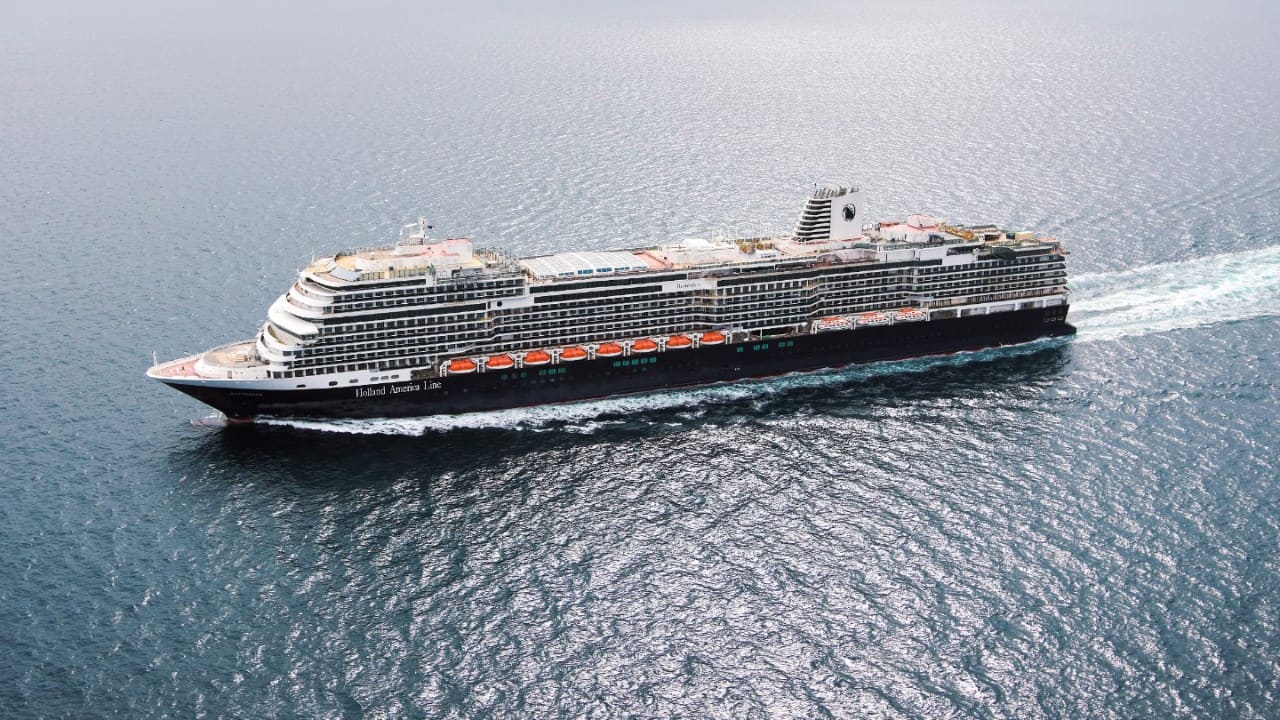 Person stretching in bed inside a Holland America cruise stateroom.