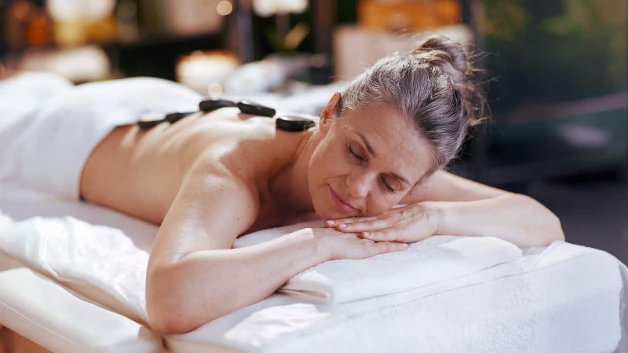 Guest enjoying hot stone massage with stones arranged on the back area at Holland America spa.