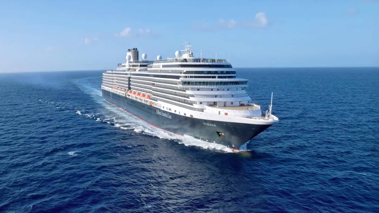 Large cruise ship sailing through open blue ocean under a clear sky.