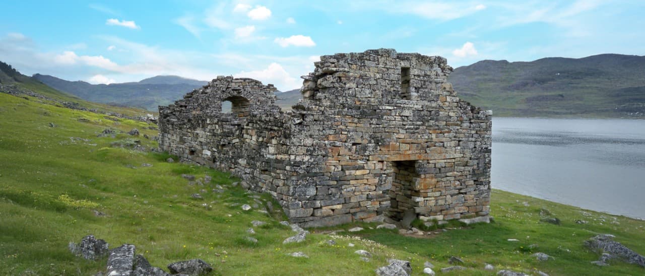 A view of the Hvalsey church ruins with water in the background.