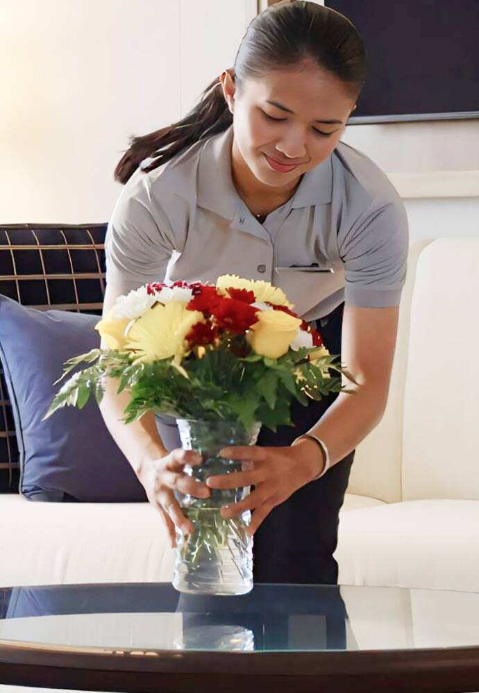 A staff member arranging flowers in a guest room.